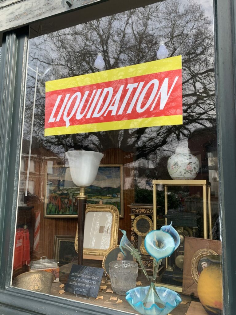 Photo de la devanture de la boutique sur laquelle est collée un écriteau "LIQUIDATION"